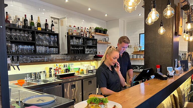 Tommy's Braterei in Bad Kissingen - Jean-Luc Schmittutz mit einer Kollegin bei der Arbeit hinter der Theke. Tommy's Braterei in Bad Kissingen - Jean-Luc Schmittutz mit einer Kollegin bei der Arbeit hinter der Theke.