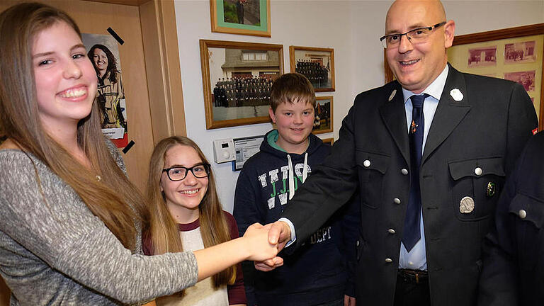 Mit traditionellem Handschlag begrüßte Kommandant Florian Hluchy Jasmin Lange (links), Laura Zeller und Julian Glück, die ihren Weg zur Feuerwehr fanden. Fotos: Gerd Schaar       -  Mit traditionellem Handschlag begrüßte Kommandant Florian Hluchy Jasmin Lange (links), Laura Zeller und Julian Glück, die ihren Weg zur Feuerwehr fanden. Fotos: Gerd Schaar