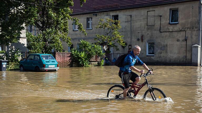 Hochwasser in Polen       -  Ein Mann fährt mit dem Fahrrad durch eine überflutete Straße in der Stadt Lewin Brzeski im Süden Polens. (Foto aktuell)