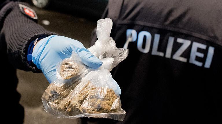 Ein Polizist zeigt in Tüten verpacktes Marihuana. Kiloweise hat ein Dealer aus NRW von 2015 bis 2017 zwei Schweinfurter Abnehmer mit 'Gras' beliefert. Nun wurde er dafür verurteilt.