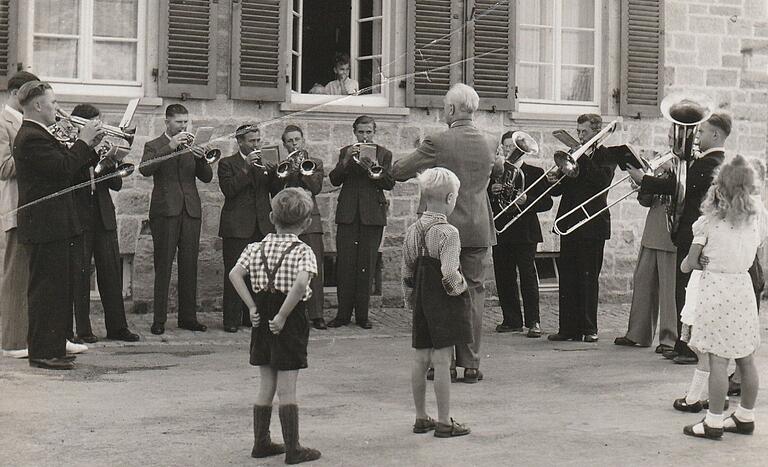 Auf dem Foto aus den 1950er Jahren ist der Posaunenchor unter Leitung von Carl Klenk beim Morgenblasen vor dem Pfarrhaus in Sennfeld. Links außen spielt Trompeter Hermann Heinemann, Klenks Nachfolger als Chorleiter.