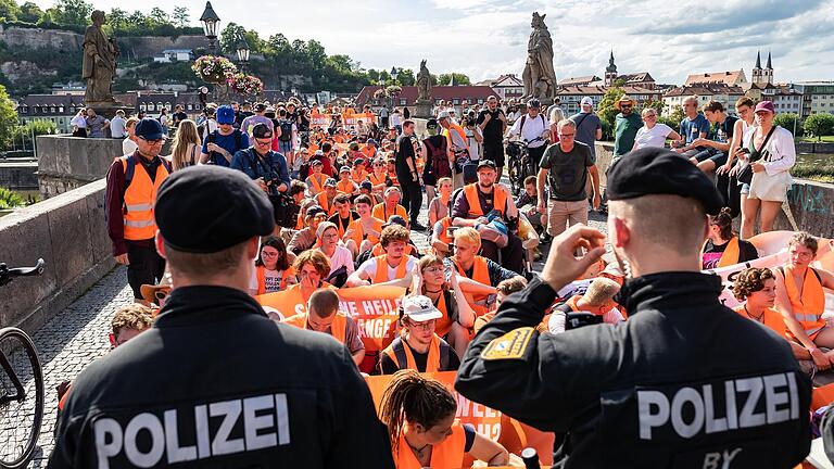 Bei über 30 Grad und Sonnenschein blockierte die Letzte Generation eine Stunde lang die Alte Mainbrücke in Würzburg.