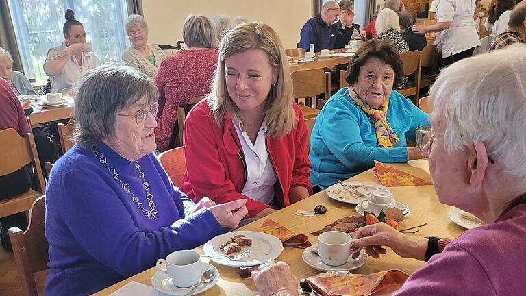 Pflegemitarbeiterin Jolana im Gespräch mit zwei Gästen beim Herbstfest der Caritas-Sozialstation St. Klara.