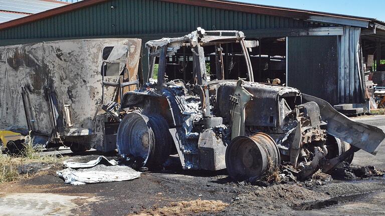 Brand in Herschfeld: Ein völlig ausgebrannter Traktor mit Anhänger steht vor dem Gebäude. Brand in Herschfeld: Ein völlig ausgebrannter Traktor mit Anhänger steht vor dem Gebäude.