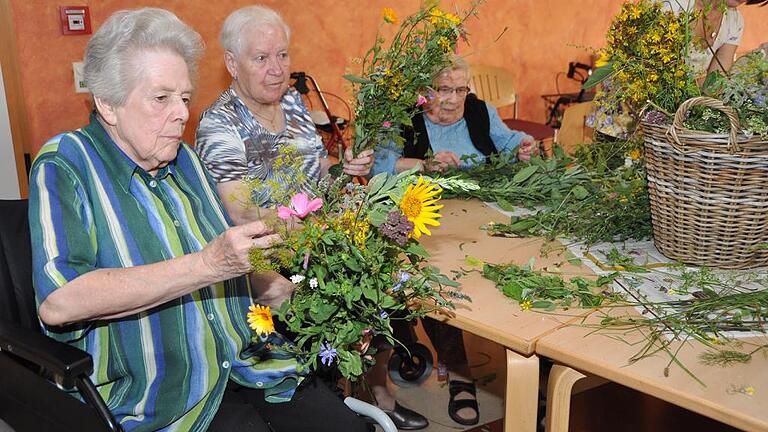 Seniorinnen des St. Thekla-Heimes in Würzburg schwelgten gemeinsam mit Kräuterpädagogin Barbara Kuhn in Erinnerungen und banden Kräuterbüschel. Foto: Wilma Wolf