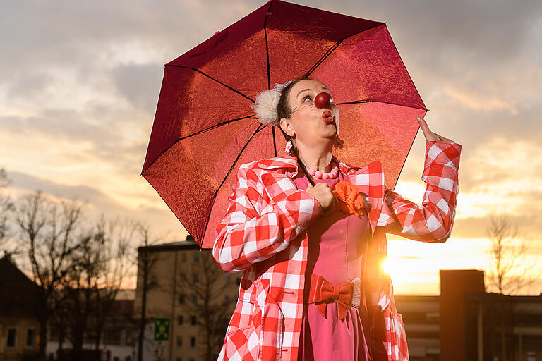 Silvia Kirchof (50) aus Gerolzhofen, von der Chanson-Sängerin zur Klinikclownin   „Für einen Moment war wirklich der Boden unter den Füßen weg“, sagt Silvia Kirchhof und hält kurz inne. „Als Künstlerin ist man ja gewohnt, dass nicht immer Unmengen an Geld reinkommen. Aber aktuell ist halt echt wenig!“, fügt sie hinzu. Anfang 2020 hatte die hauptberufliche Chansonsängerin und Theaterleiterin einen vollen Terminkalender. Ein großes Theaterprojekt, Konzerte auf Kleinkunstbühnen, Geburtstagen, Firmenfeiern und Tagungen. Im gesamten deutschsprachigen Raum. Mit der Pandemie kommen die Absagen. Im Sommer entspannt sich die Situation. Es gibt Konzerte im Freien, kleine Gartenpartys und viel Solidarität. „Wir konnten bisschen was verdienen. Und vor allem auch mal wieder vor Publikum arbeiten“, sagt Kirchhof. Gut für die Psyche. Kurz mal aufatmen. Unter strengen hygienischen Auflagen darf Kirchhof im Herbst wieder als Klinikclownin arbeiten. Vom Balkon aus. Erst in der Würzburger Kinderklinik am Mönchberg, dann auch in der Universitätskinderklinik. „Das war für mich existenziell, Beruf und Berufung“, sagt Kirchhof. Endlich darf sie wieder was geben. Und es kommt auch was zurück. Schnell zeigt sich, dass die Klinikclownerie auch auf dem Balkon sehr wertvoll ist. Die Kinder sind isoliert, nur ein Elternteil kann zu Besuch kommen, keine Freunde, keine Geschwister, keine Großeltern. „Dann ist die Viertelstunde am Fenster Gold wert“, sagt Kirchhof.