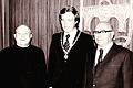 Aufnahme im großen Sitzungssaal des &bdquo;neuen&rdquo; Rathauses &ndash; an der Wand das stilisierte Stadtwappen. Das Foto stammt aus dem Jahr 1973 und zeigt Bürgermeister Armin Grein mit seinem Amtsvorgänger Ulrich Willer (rechts) und Pfarrer Franz Hegmann (links), damals beide Ehrenbürger der Stadt.