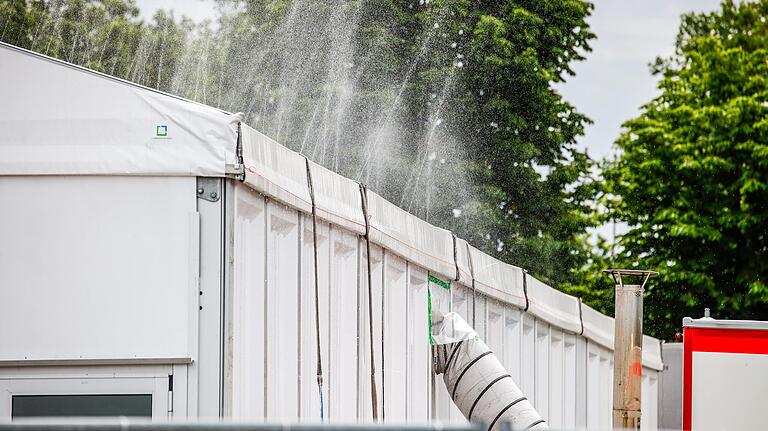 Mit Hilfe einer Sprinkleranlage kühlte die Feuerwehr am Sonntag das Zeltdach des Impfzentrums, außerdem wurde abgekühlte Außenluft ins Zelt geblasen. Mit Hilfe einer Sprinkleranlage kühlte die Feuerwehr am Sonntag das Zeltdach des Impfzentrums, außerdem wurde abgekühlte Außenluft ins Zelt geblasen. 
