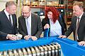Die beiden URT-Geschäftsführer Peter Heßler (links) und Thomas Gundersdorf (rechts) erklären Martin Schulz und Kerstin Westphal eine Zerkleinerungsmaschine und das Ergebnis: hier beispielsweise Aluminium- und Kunststoff-Granulat.&nbsp;