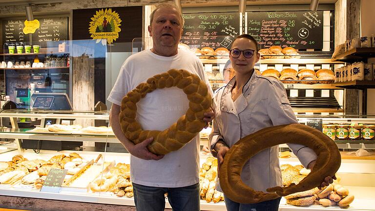 Das fertige Produkt: Bäcker Jürgen Kleespies mit seiner Angestellten Ann-Kathrin Thiele und zwei frisch gebackenen, unterschiedlich geformten Neujahrsbrezeln.