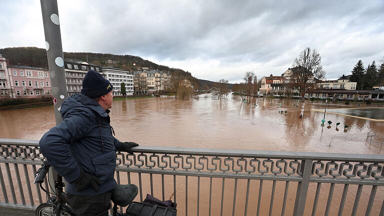 Hochwasser in Unterfranken.jpeg       -  Ein Mann schaut von einer Brücke auf den vom Hochwasser der Fränkischen Saale überschwemmten Kurpark.