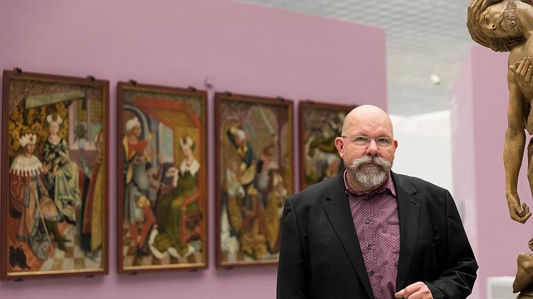 Blick in die Sonderausstellung „Riemenschneider X Stoss – Schnittpunkt Münnerstadt“ im Museum am Dom. Im Hintergrund die Gemälde von Veit Stoß, rechts ein Detail des 'Gnadenstuhls' von Riemenschneider. Dazwischen Kurator Wolfgang Schneider.