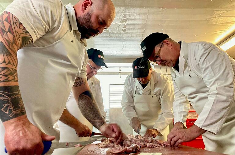 Echte Handarbeit für den Drei-Franken-'Bresssagg': Metzgermeister Sebastian Rückel schneidet gemeinsam mit den Bürgermeistern Armin Luther (Burghaslach), Johannes Krapp (Schlüsselfeld) und Ernst Nickel (Geiselwind) Fleisch und Schwarte klein (von links).