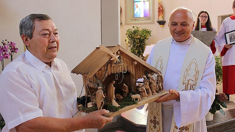 Kirchenpfleger Manfred Dietz (links) überreicht sein Abschiedsgeschenk an den scheidenden Pfarrer Wiktor Dziedziech &ndash; eine handgeschnitzte Rhöner Weihnachtskrippe.