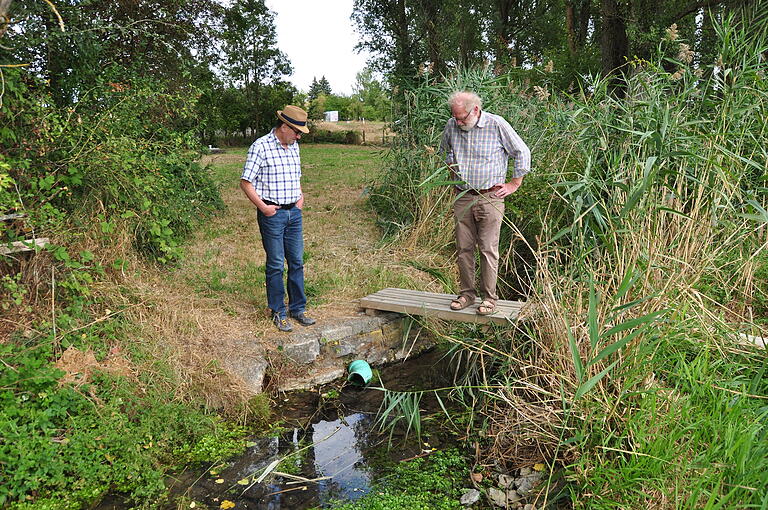 Der Floßgraben ist der Überlauf der einstigen Trinkwasserquelle für Roßbrunn und Uettingen. Heute ist sie der Überlauf des Notbrunnen, der im Katastrophenfall die Bevölkerung mit Trinkwasser versorgen soll. Aufgrund der großen Trockenheit der vergangenen Wochen läuft kaum sichtbar Wasser in den Floßgraben. (von links) Stellvertretender Vorsitzender  Richard Fuchs und Vorsitzender Hans Madinger der BI. Foto: Elfriede Streitenberger