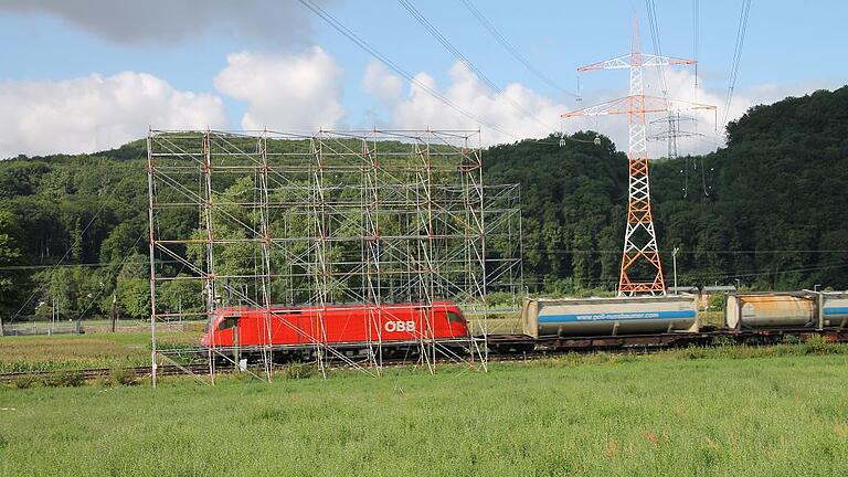 Wie hier an der Bahnstrecke bei der Staustufe Harrbach stehen zur Zeit viele sogenannte Schleifgerüste an Straßen und Zugstrecken, die der Sicherheit beim Austausch der durch den Landkreis laufenden Höchstspannungsleitung zwischen Bergrheinfeld und Aschaffenburg dienen.