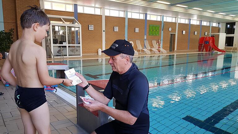 Schwimmlehrer Kurt Kegler überreicht einem kleinen Jungen sein Seepferdchen-Abzeichen mit einer kleinen Urkunde. Schwimmlehrer Kurt Kegler überreicht einem kleinen Jungen sein Seepferdchen-Abzeichen mit einer kleinen Urkunde.