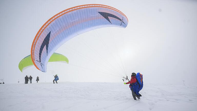 Wintereinbruch in der Rhön: Zwei Paraglider übten am Sonntag zwischen Radom und Fliegerdenkmal auf der Wasserkuppe. Bei Schneefall und eisiger Kälte zog es zahlreiche Touristen in die Rhön.