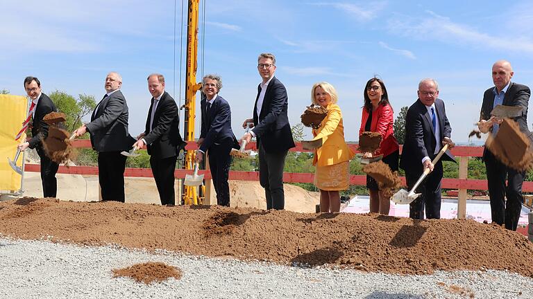 Neun Männer und Frauen greifen im Mai 2023 auf der Baustelle des Kitzinger Staatsarchivs feierlich zum Spaten. Das Projekt ist mit 75 Millionen Euro veranschlagt.