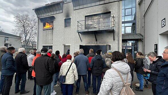 Die Rottendorfer Besuchergruppe vor dem Brandhaus mit Feuer im ersten Stock und der Autogarage.