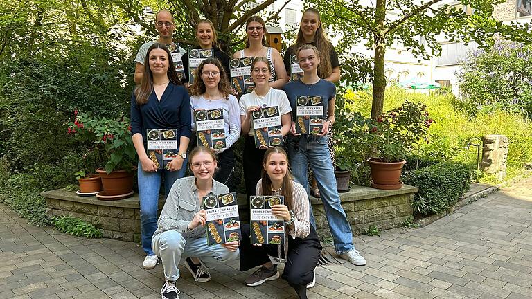Die Teilnehmerinnen des P-Seminars 'Klimakochbuch' freuen sich im Garten der St.-Ursula-Schule über ihr gelungenes Projekt.