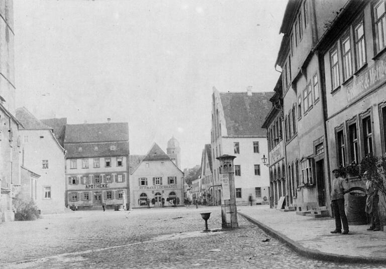 Der Marktplatz von Gerolzhofen vor 1900: eine freie Fläche mit zwei Brunnen, einer vor dem Gasthaus 'Wilder Mann' (rechts) und ein zweiter hinten vor der Apotheke (mit einem hellen Brunnengehäuse). Autos waren damals noch kein Thema.