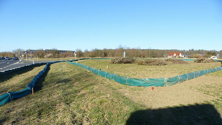 Bauarbeiter ziehen lange Eidechsenzäune im Kreuzungsbereich. Im Hintergrund ein kombiniertes Holz- und Mahdlager für die Zauneidechse Bauarbeiter ziehen lange Eidechsenzäune im Kreuzungsbereich. Im Hintergrund ein kombiniertes Holz- und Mahdlager für die Zauneidechse