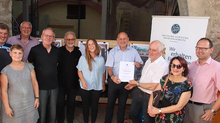 Grund zum Strahlen: Reinhold Schöpf von der Stiftung Denkmalschutz überreichte Bürgermeister Paul Kruck eine Förderung von 50 000 Euro für die Sanierung des Hauses Hauptstraße 9. Mit ihnen freuen sich Mitglieder des Stadtrats, Beatrix van Venrooy vom Heimatverein, Jürgen Lenssen sowie die Architekten Alfred und Silja Wiener.