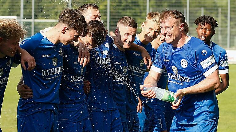 Stefan Wasser (rechts) vom FV 04 Würzburg besprüht seine Mitspieler nach dem Sieg beim Jubeln mit den Fans vor der Tribüne. Die Würzburger gewannen das Rückspiel in der zweiten Runde der Bayernliga-Relegation auf der Sepp-Endres-Sportanlage mit 5:0.