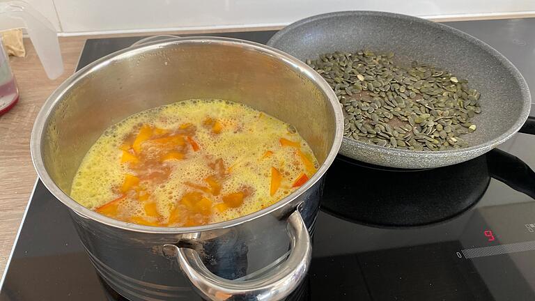 Während die Kürbisstücke in der Hühnerbrühe kochen, kann man die Kerne in einer Pfanne rösten, bis sie zu springen beginnen. Während die Kürbisstücke in der Hühnerbrühe kochen, kann man die Kerne in einer Pfanne rösten, bis sie zu springen beginnen.
