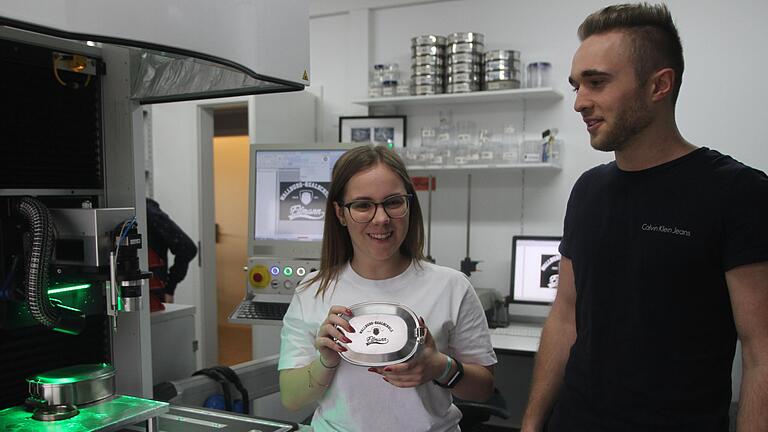 Vorstandsvorsitzende Melina Hüpschle zeigt eine gravierte Brotzeitdose mit Wirtschaftspaten Adrian Dümpert (rechts).