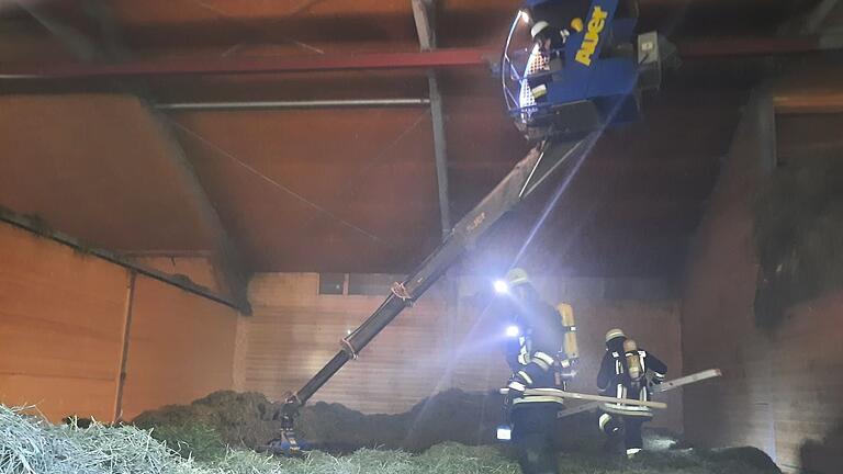 Feuerwehrleute auf der Suche nach dem Schwelbrand in der Halle, in der das Heu gelagert ist.