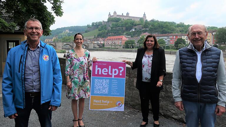 Hilfsangebot in  neun Sprachen: Michael Lindner-Jung, der Leiter der Bahnhofsmission, Sozialreferentin Hülya Düber, Integrationsbeauftragte Christine Blum-Köhler und Helmut Fries, der Vorsitzende des Fördervereins Bahnhofsmission, mit einem Plakat, das „Help“ anbietet, ein Wort das international verstanden wird.