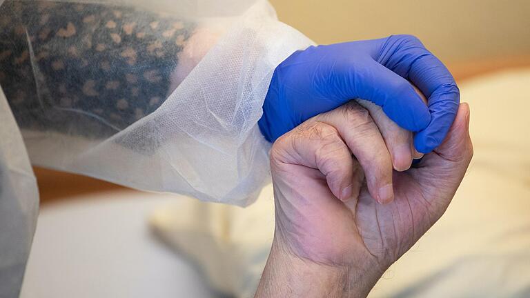 Eine Altenpflegerin hält die Hand eines Heimbewohners. Eine Altenpflegerin hält die Hand eines Heimbewohners.