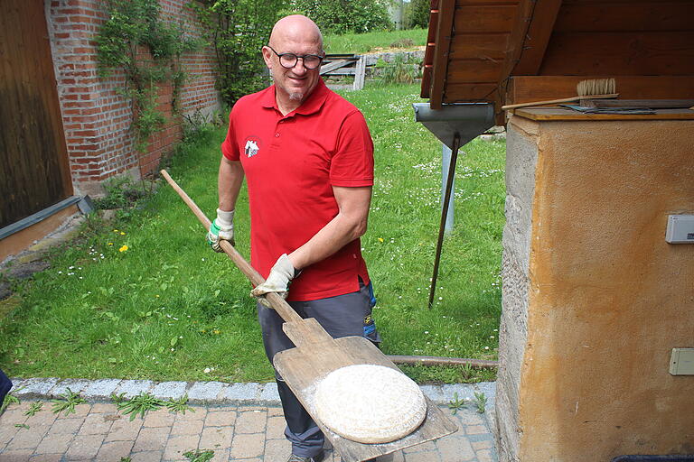 Roland Kuhn schiebt den mitgebachten Brotteig in Prüßberg der Reihe nach in den Ofen.