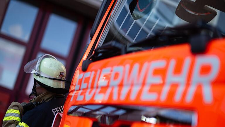 Feuerwehrmann steht neben einem Feuerwehrauto (Symbolbild)       -  Die Ursache des Brandes ist noch unklar, die Polizei vermutet einen technischen Defekt. (Symbolbild)