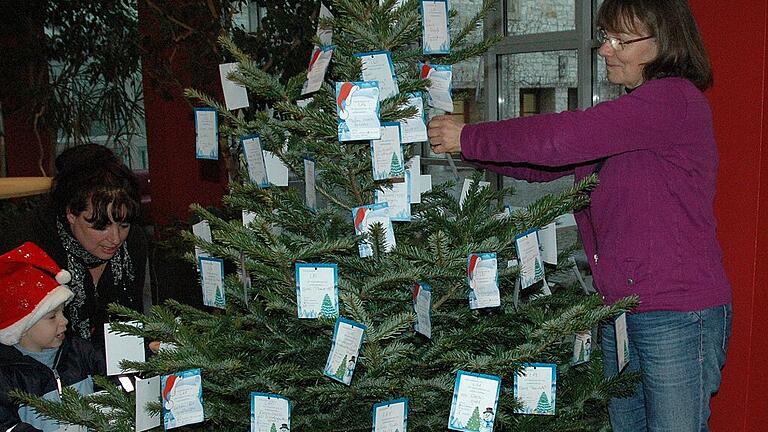 Ein Foto von einer früheren Wunschbaumaktion: Während Elisabeth Cichon vom Familienbüro Wunschzettel an einen Baum hängt, nimmt eine Besucherin des Landratsamts mit ihrem Sohn die Zettel unter die Lupe. Ein Foto von einer früheren Wunschbaumaktion: Während Elisabeth Cichon vom Familienbüro Wunschzettel an einen Baum hängt, nimmt eine Besucherin des Landratsamts mit ihrem Sohn die Zettel unter die Lupe.