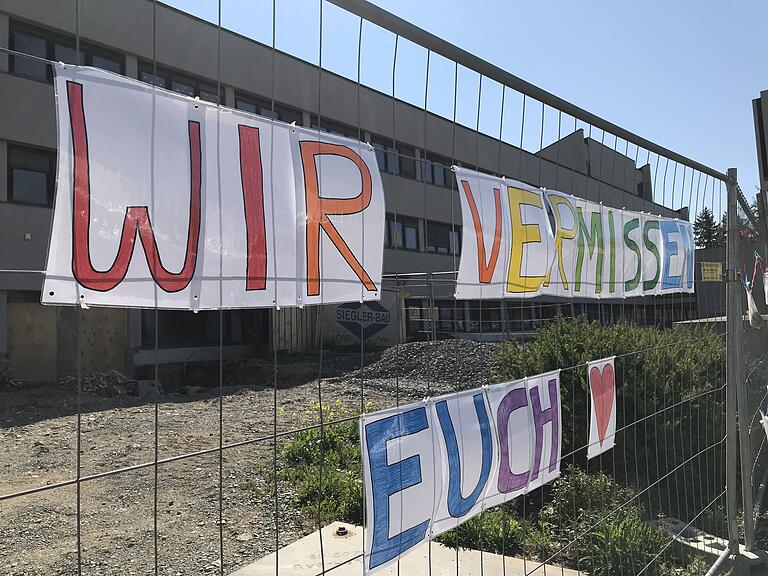 'Wir vermissen euch' am Bauzaun des Kindergartens zur Heiligen Familie in Karlstadt.