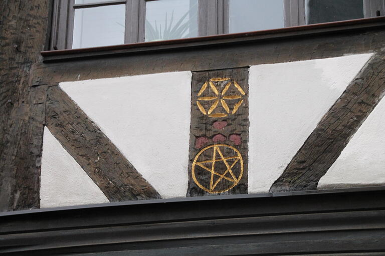 Ein Pentagramm (unten) und ein weiteres Zeichen zieren einen Balken des Fachwerks.