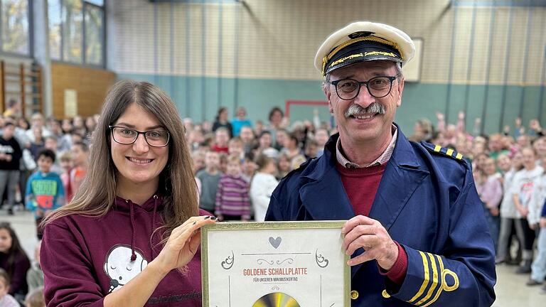 Auf dem Foto: Cassy von den Minimusikern überreicht dem Rektor Frank Maier die goldene Schallplatte für den Minimusikertag.