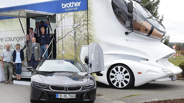 Colani-Truck erregt Aufsehen       -  Große Augen gab es, als zu einem Schautag von Papier Schmitt ein futuristisch gestylter Lkw aufs Firmengelände in Salz fuhr. Das vom einstigen Stardesigner Luigi Colani entworfene Gefährt stand im Mittelpunkt des Event-Tags und war vom Druckerhersteller Brother mit einem Schauroom und seinen aktuellen Geräten ausgestattet worden. Neben dem augenfälligen Brummi stand ein BMW i8 für Probefahrten zur Verfügung. Der Hybrid-Bolide aus München steht für die aktuelle Feinstaubdiskussion, die sich nach Ansicht von Geschäftsführer Rainer Müller nicht nur auf die Straße sondern auch auf das Büro beziehen sollte. An den Schreibtischen sei die Belastung für die Mitarbeiter bei Verwendung von Druckern ohne Filter höher als an stark befahrenen Straßen, gab Schmitt zu bedenken. Der Betreiber des Showtrucks habe diesen Umstand längst erkannt und die entsprechenden Vorkehrungen getroffen. Außerdem informierten die Mitarbeiter über die neue Generation von Büromöbel. Foto: Heise