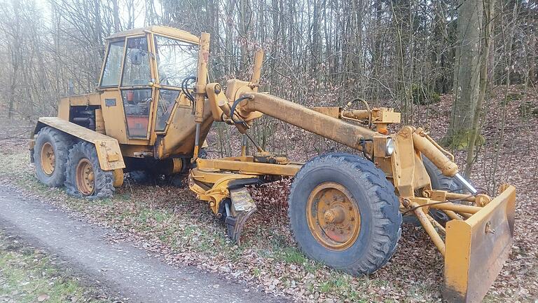 Diese Baumaschine steht mit platten Reifen im Wald bei Untersambach. Die Besonderheit erschließt sich nicht auf den ersten Blick.