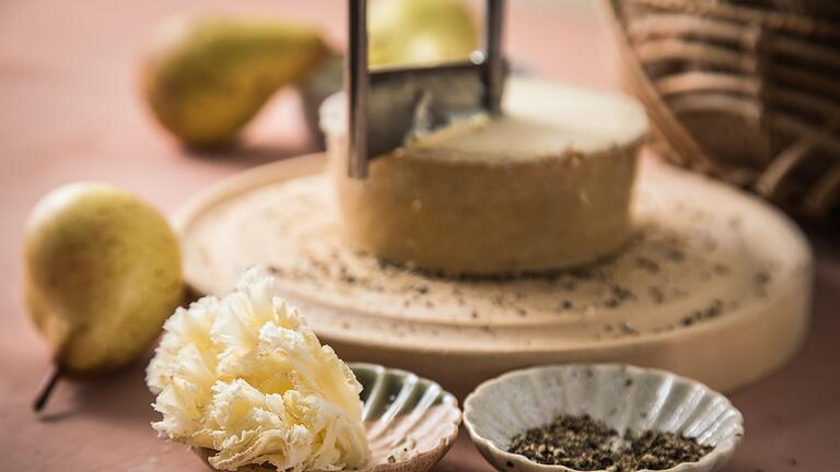 Girolle mit Tete de Moine       -  Mit der sogenannten Girolle, einem kurbelähnlichen Käsehobel, wird der Tête de Moine hauchdünn geschnitten. Raffinierter wird es, wenn der Mönchskäse schon vor dem Hobeln mit schwarzem Pfeffer bestreut wird.