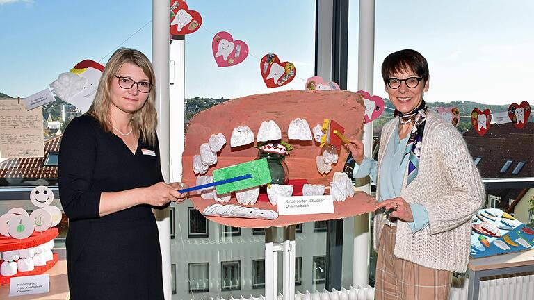 Gebiss-Modell aus dem Kindergarten St. Josef in Unterbalbach: Jugendzahnärztin Cosima Lang-Lebakken (links) und Sozialdezernentin Elisabeth Krug besichtigen die Kunstwerke zum Tag der Zahngesundheit im Landratsamt.
