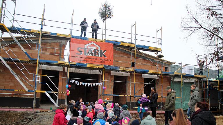 Feierliches Richtfest am Alitzheimer Kindergarten Sankt Martin: Dem humorvollen Richtspruch von Zimmermann René Stark (oben links) lauschen die Mädchen und Buben mit ihren Erzieherinnen und vielen Gästen.