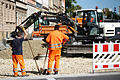 Rechtsstreit um Straßenausbau       -  ARCHIV - Zwei Bauarbeiter schauen am 09.10.2014 ihrem Kollegen in einem Bagger beim Verteilen von Kies an einer Baustelle in Bamberg (Bayern) zu. Freie Wähler-Chef Hubert Aiwanger plant ein Volksbegehren gegen die in vielen Gemeinden heftig umstrittenen Straßenausbaubeiträge. (zu dpa «Aiwanger plant Volksbegehren gegen Straßenausbaubeiträge» vom 30.11.2017) Foto: David Ebener/dpa +++(c) dpa - Bildfunk+++ | Verwendung weltweit