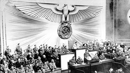 &bdquo;Seit 5 Uhr 45 wird jetzt zurückgeschossen!&ldquo;: Adolf Hitler (am Rednerpult) begründet in seiner Rede vor dem Reichstag in Berlin am 1. September 1939 den Angriff auf Polen, mit dem der Zweite Weltkrieg begann.