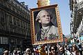 Proteste zum 1. Jahrestag der Amtseinführung von Macron       -  Vor dem ersten Jahrestag der Amtseinführung von Präsident Emmanuel Macron kommt es in Paris zu Protesten Zehntausender Menschen. Demonstranten haben am Samstag ein Gemälde dabei, das den Präsidenten als König Ludwig XVI. zeigt.