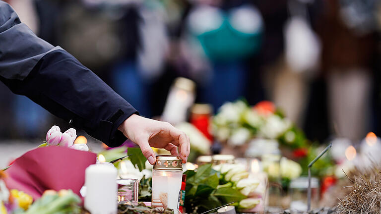 25.01.2022, Baden-Württemberg, Heidelberg: Menschen legen vor einem Gebäude der Universität Blumen und Kerzen an den Wegesrand. Gestern war ein 18 Jahre alter Student mit einer Schrotflinte bei laufender Vorlesung in den Hörsaal des Gebäudes gestürmt und hatte um sich geschossen. Eine junge Frau starb, der Täter tötete sich wenig später selbst. Foto: Uwe Anspach/dpa +++ dpa-Bildfunk +++