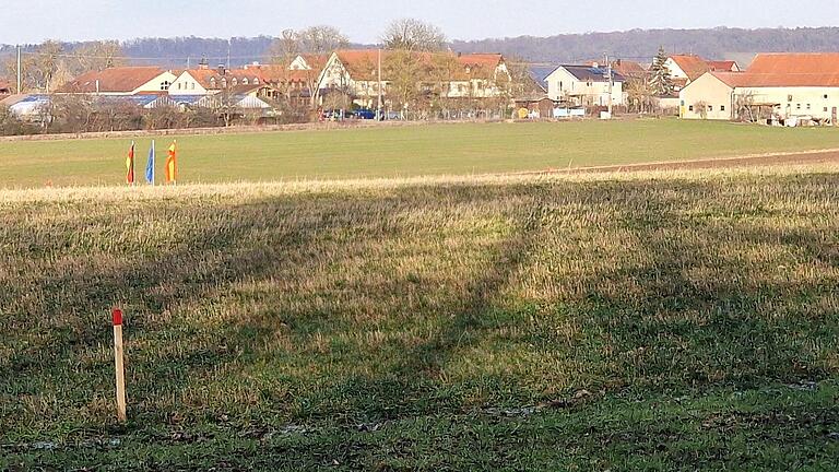 Blick auf Gadheim, links die Fahnen des  EU-Mittelpunkts und  dahinter der Markushof, rechts vorne der Eckpflock des geplanten Aussiedler-Wohnhauses